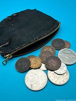 Group view: worn black zip coin purse with 13 assorted coins spread in front