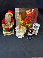Group shot showing all five items: puzzle box, tin Santa toy, polar bear music box, glass Santa bell, boxed Leafs ornament