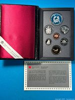 Open booklet showing red satin pouch, coin array, and certificate