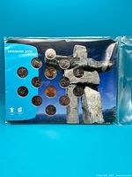 Front of sealed presentation card showing all coins mounted against inukshuk background