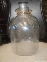 Front view of clear one-gallon glass bottle showing shape and cap