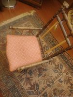 Front angled view of antique child’s chair showing turned wood frame and upholstered seat