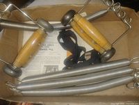 Box containing wooden-handled chest expander and loose springs