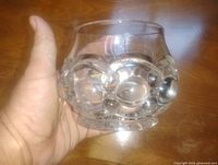 Side view of clear crystal bowl held in hand showing bubble motifs