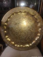 Front view of brass tray showing detailed etching and scalloped rim