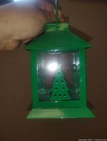 Front view of green metal lantern with Christmas tree cut-out and glass panels