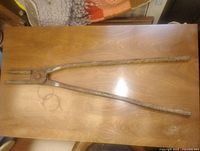 Full view of 24" forged iron tongs on tabletop