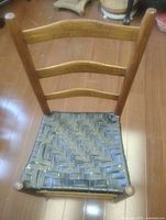 Front view of chair showing ladder back and woven leather seat