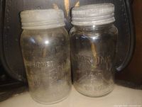 Front view of two Clear Improved Corona jars with lids
