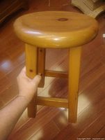 Full view of pine stool, round seat, hand for scale