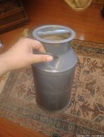 Full view of grey steel milk can showing top lid and embossing