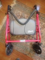 Top view of folded red rollator walker showing grey Evolution seat and front wheels