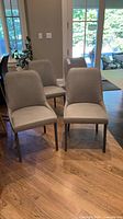 Four matching taupe upholstered dining chairs around table