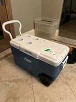 Cooler side view showing wheels, handle, lid with cup holders