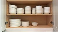 Cabinet shelves showing stacked white plates and bowls