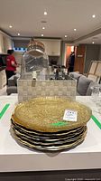 Stack of eight gold charger plates, drink dispenser, cutlery in bin