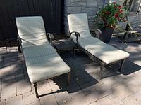 front view of two cast iron chaise loungers with cushions and side table