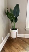 Full view of planter on stand with faux plant in corner