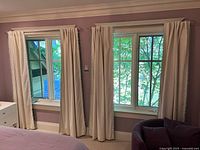 Two windows dressed with ivory curtains showing full length and trim