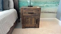 Front view of Handstone wood nightstand beside bed