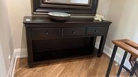 Front view of dark wood sideboard with three drawers and lower shelf
