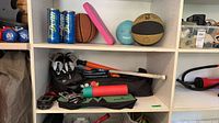 Shelf view showing balls, tennis ball cans, shoes, bats, mats