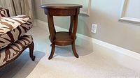 side view of round wood side table beside chair