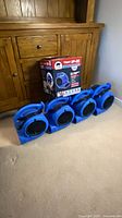 Four blue B-Air VP-20 air movers lined on floor under cabinet