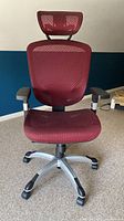 Front view showing burgundy mesh seat/back, black frame, silver base and casters