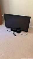 Front view of LG 47" LCD TV on stand with remote and power cord