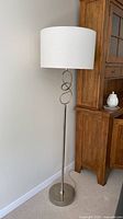 Full view of floor lamp showing shade, swirl accent, pole and base