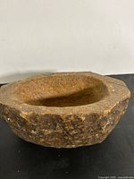 Angled top view of rough-hewn stone grinder showing carved interior