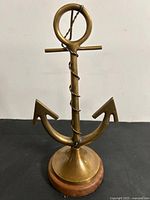 Front view of brass anchor ornament on wood base