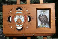 Front view showing carved and painted Salish design and photo window with eagle image
