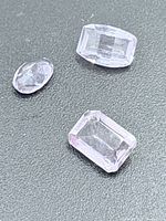Close-up of three loose amethyst gemstones showing shapes and faceting