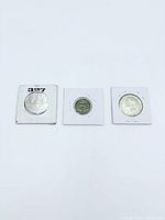 Three coins in cardboard flips aligned horizontally