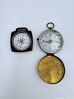 Square wooden compass and brass pocket compass opened