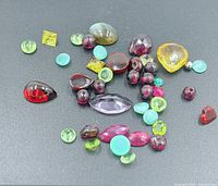 Group shot of all loose gemstones on dark background showing variety of colours and cuts