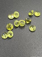 Close-up of 11 faceted peridot stones on black surface