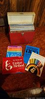 Open flip-top record case showing vinyl records and guitar books in front