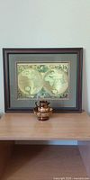 Framed gold map print with luster pitcher and bowl on shelf