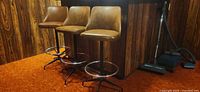 Three brown vinyl swivel bar stools at bar