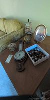 All items grouped on tabletop: barometer, stones, glass sphere, plate, art on easel, china box