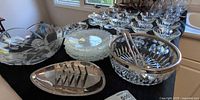 Assorted glassware on table including bowls, plates, divided tray, and champagne coupes