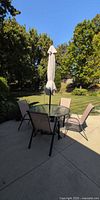 Full patio set showing table, umbrella and four chairs on patio