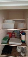 Cupboard shelves showing variety of plastic containers and three insulated bottles