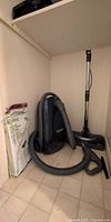 Overall view of Kenmore canister vacuum with hose, wand, powerhead, extra tool and package of bags
