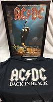 Framed AC/DC Let There Be Rock poster with Back in Black T-shirt displayed