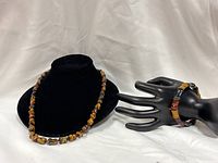 Necklace on display stand, bracelet on mannequin hand