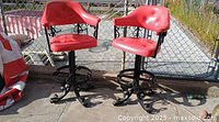 Two red vinyl swivel bar stools, full view